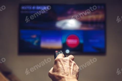Preview: elderly man hand holding TV remote control.