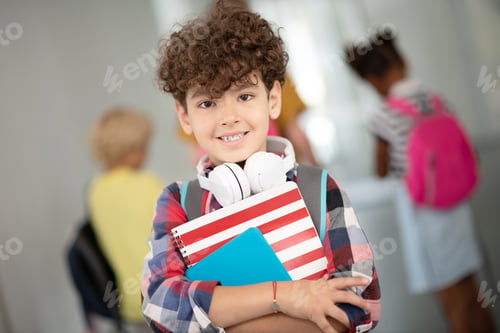 Preview: Dark-eyed curly boy holding notebook and tablet