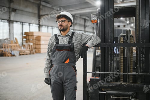 Preview: Arab engineer leaning on forklift in modular house production workshop
