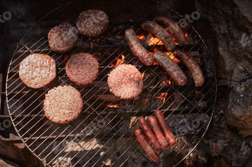 Preview: Burgers and sausages cooking on campfire