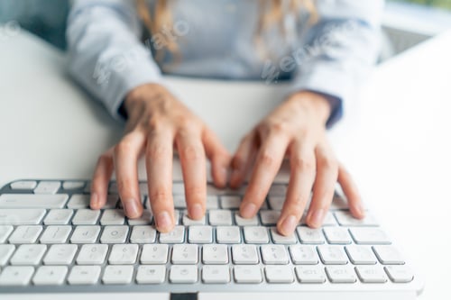 Preview: top shot close-up in a modern office female worker in a blue shirt sitting at a table directly