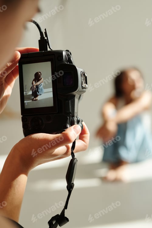 Preview: Focus on screen of photocamera held by young professional female photographer