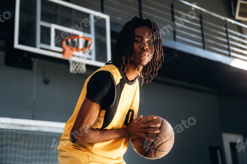 Preview: There is hoop high up. Young black man is playing basketball indoors