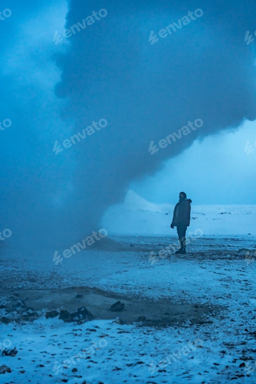Preview: A man stands next to one of the steaming fumaroles at Hverir or Namafjall geothermal park in winter