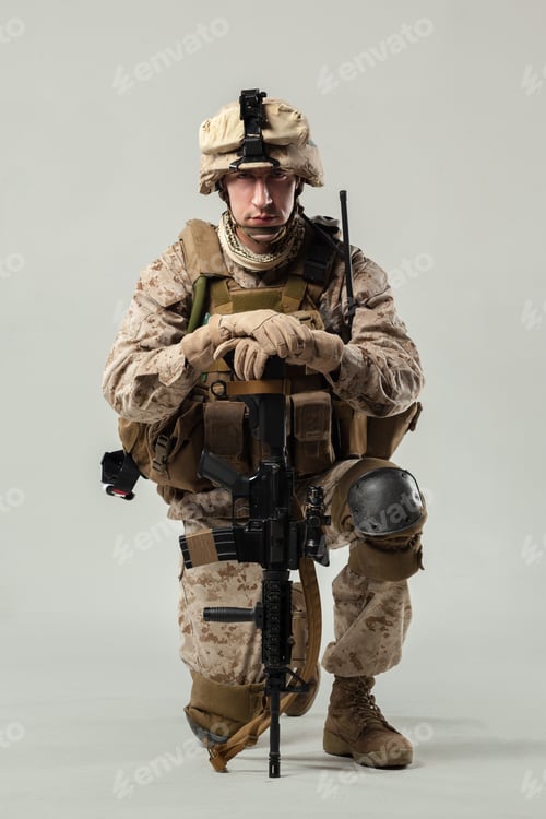 Preview: Military soldier kneeling with weapon and equipment in studio setting