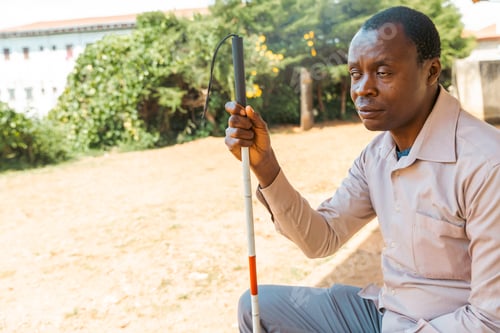 Preview: A man with a cane sits on the a bench, portrait of a person suffering from blindness