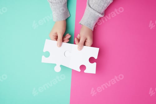 Preview: Two empty paper white pieces of puzzles in female hands, puzzle connected