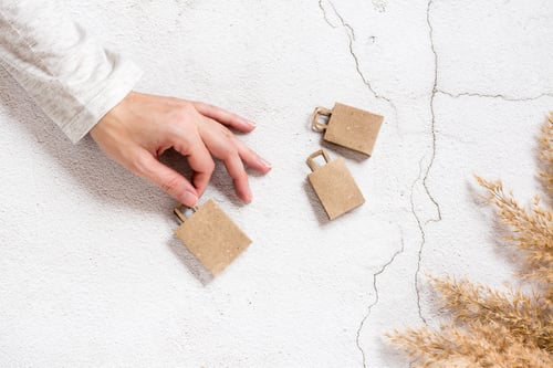 Preview: A woman's hand holds paper craft shopping bags on a concrete background. Top view.