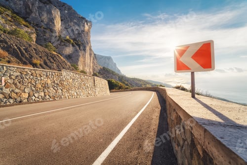 Preview: Asphalt road and road sign in mountains at sunset