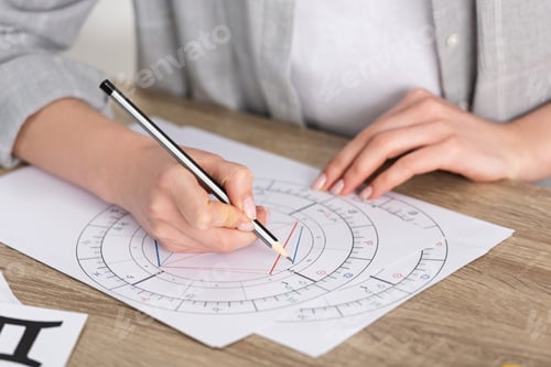 Preview: Cropped view of astrologer drawing natal chart on wooden table
