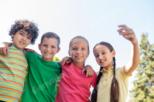 Preview: Embracing smiling school age friends outdoors