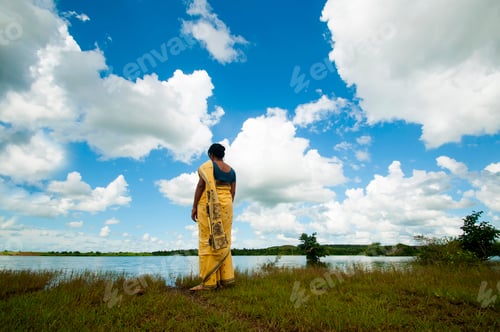 Preview: Indian woman alone in front of lake and enjoying the colors of nature.