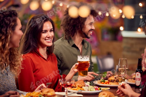 Preview: Multi-Cultural Group Of Friends Enjoying Night Out Eating Meal And Drinking In Restaurant Together