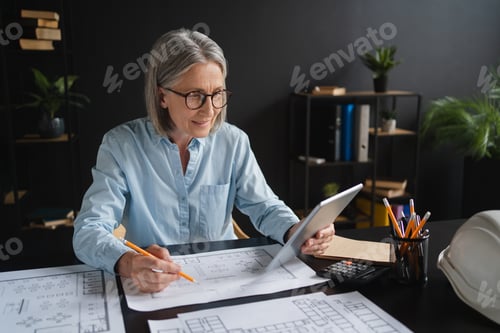Preview: Focused woman designer engineer working on new residence complex architectural project using tablet.