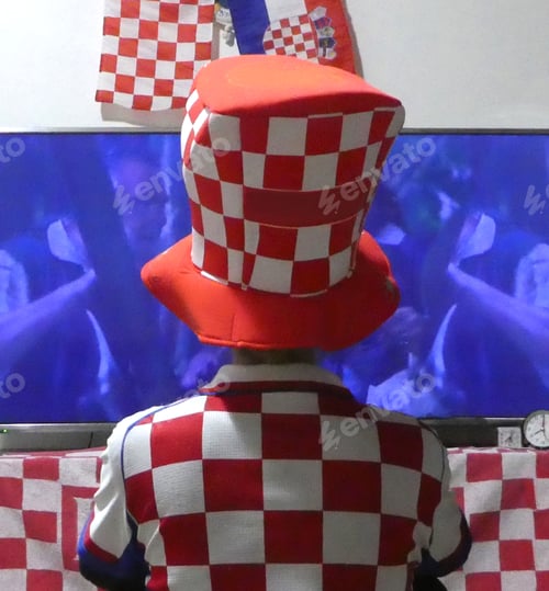 Preview: Football fan wearing Croatian soccer jersey watching game on screen