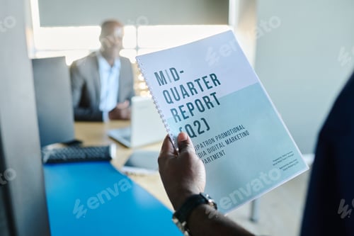 Preview: Close-up of young male economist holding mid-quarter report