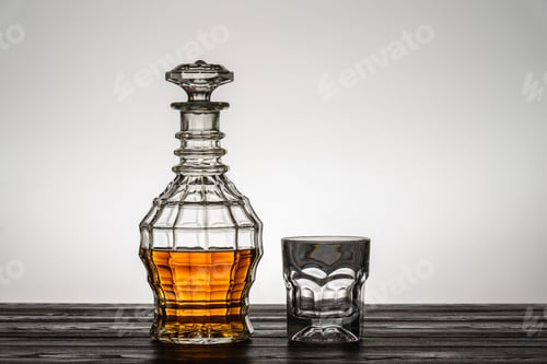 Preview: Old style vintage whiskey decanter and a glass on wooden table