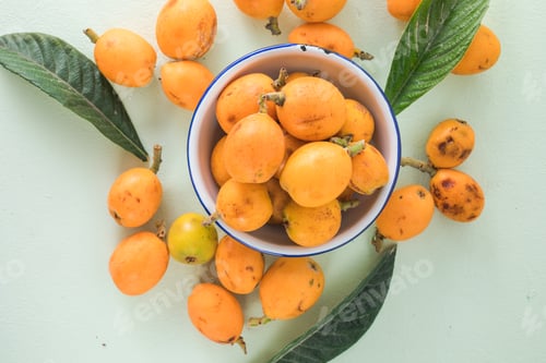 Preview: Ripe medlar fruit , Eriobotrya japonica, and green medlar leaves on wooden table. Top view