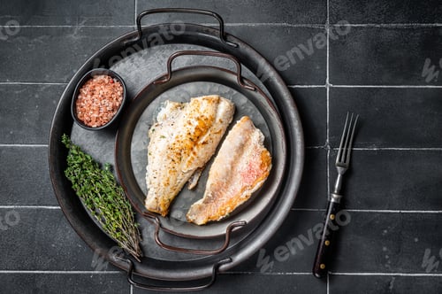 Preview: Roasted ocean red perch fillet with olive oil, thyme and spices. Black background. Top view