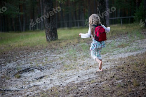 Preview: A little girl with a red backpack going through the forest trail