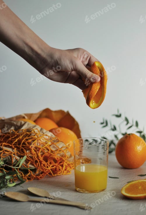 Preview: An orange slice clutched in the hand with natural juice droplets falling into the glass