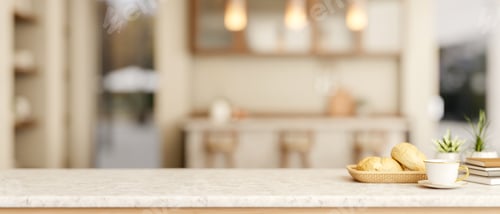 Preview: Coffee cup with breads on marble table across counter bar and cupboard in a kitchen or dining room.