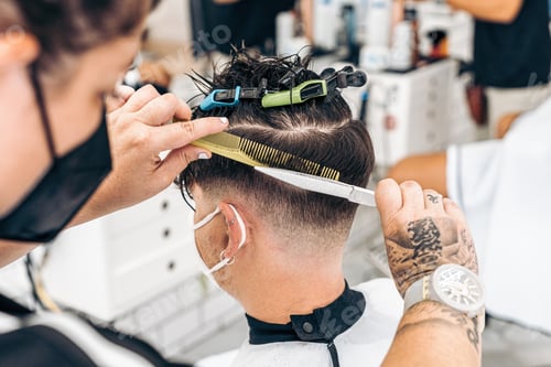 Preview: Close up view photo of a hairdresser cutting the hair of a young man