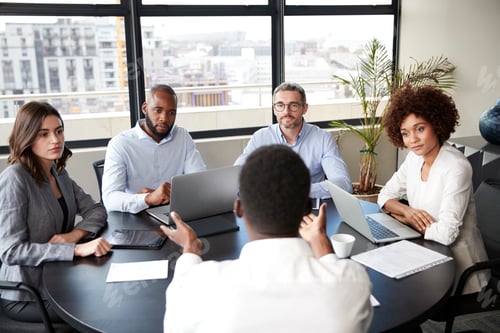 Preview: Corporate business people in a meeting room listening to a colleague speaking, elevated view