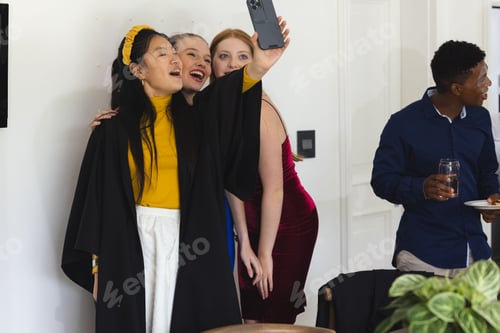 Preview: Teens celebrating graduation taking selfie at home, smiling and enjoying party