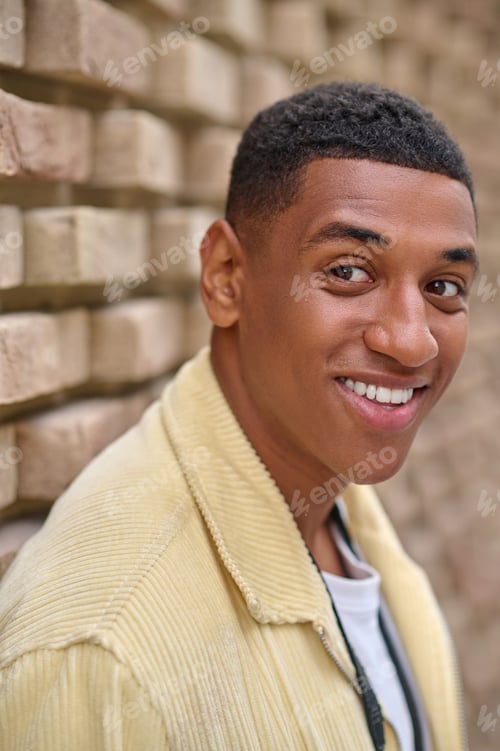Preview: Headshot of young dark-skinned man in beige jacket