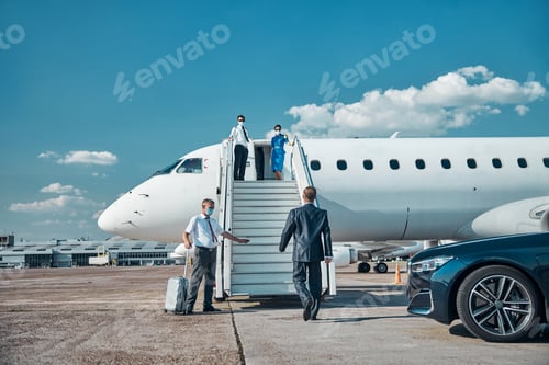 Preview: Businessman with assistant getting on plane during quarantine