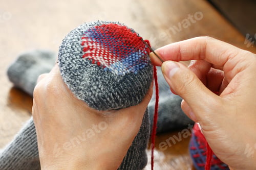 Mending a Sock with Needle and Red Thread