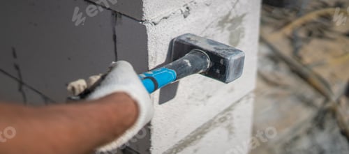 Preview: Worker with a glove strikes a concrete wall with a hammer on a construction site