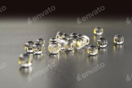 Preview: Closeup of transparent reflective jelly pills on a gray table surface