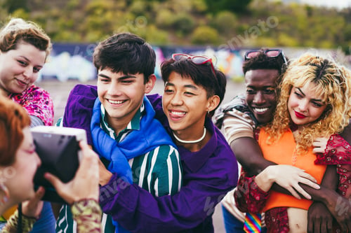 Preview: Young diverse people having fun with old vintage camera outdoor - Focus on asian guy wearing makeup