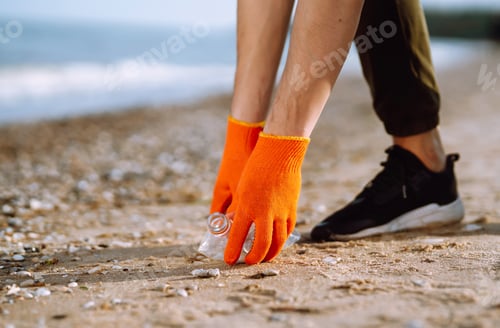 Preview: Trash on the beach. Men hand wearing protective gloves collects bottle plastic on sea beach.