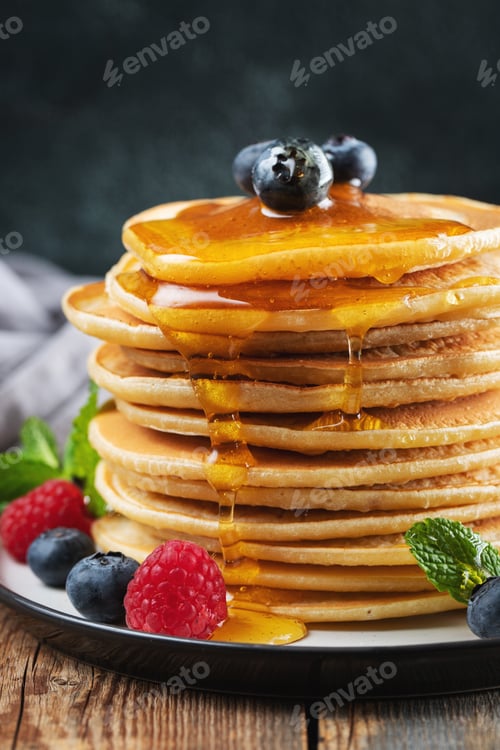 Preview: Delicious pancakes, with fresh blueberries, raspberry and maple syrup or honey on a dark background