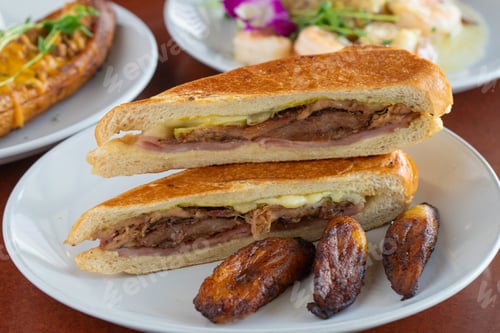 Preview: two plates of food containing a cut in half sandwich and baked potatoes