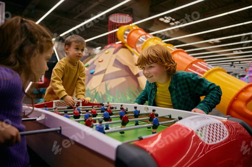 Preview: Happy excited children playing table football at entertainment center