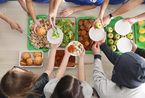 Preview: Volunteers serving food to poor people at table, top view