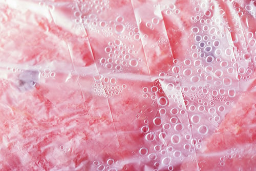 Preview: Fresh juicy pink watermelon under plastic cover with condensation bubbles