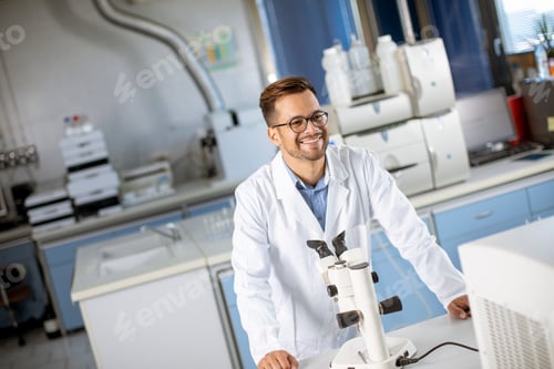 Preview: Young scientist in white lab coat working with binocular microscope in the material science lab