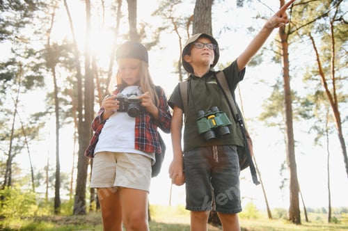 Preview: boy and girl go hiking with backpacks on forest road bright sunny day
