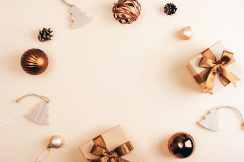 Preview: Flat lay of bronze and gold Christmas decorations, gifts, and ornaments on a soft beige background.