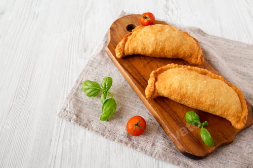 Preview: Homemade Deep Fried Italian Panzerotti Calzone on a rustic wooden board on a white wooden background