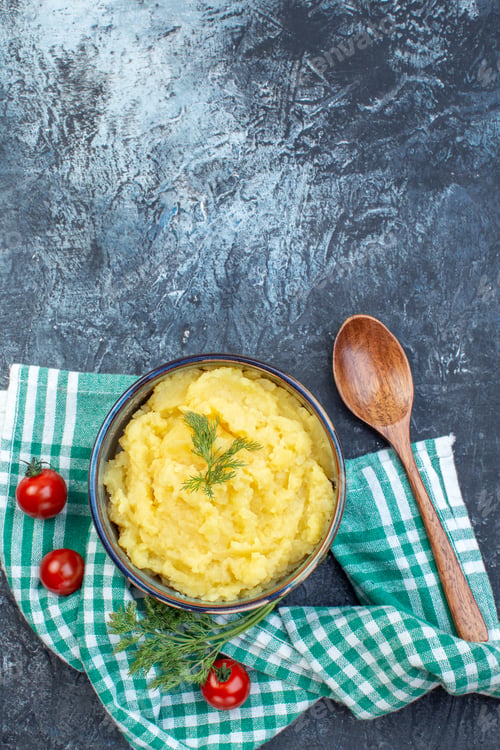 Preview: Vertical view of mashed potatoes served with dill wooden spoon fresh tomatoes on green stripped