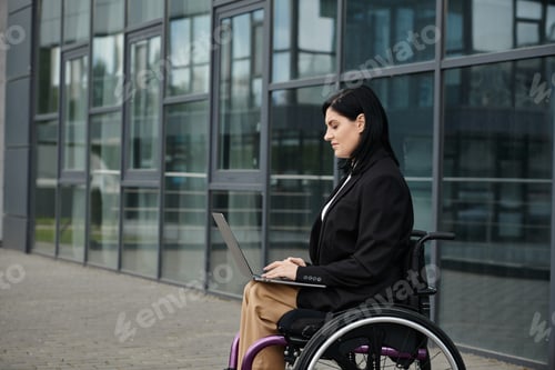Preview: Businesswoman Working on Laptop Outside Modern Office Building