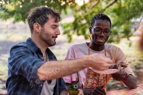 Preview: Two Men Share Food Outdoors at Picnic