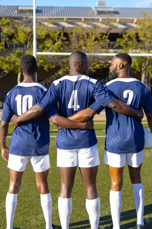 Preview: Three African American young male athletes in blue jerseys, white shorts on field outdoors