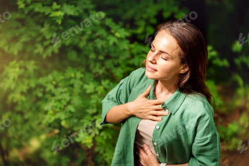Preview: high angle view of young adult woman practising breathing exercise in the forest in summer.
